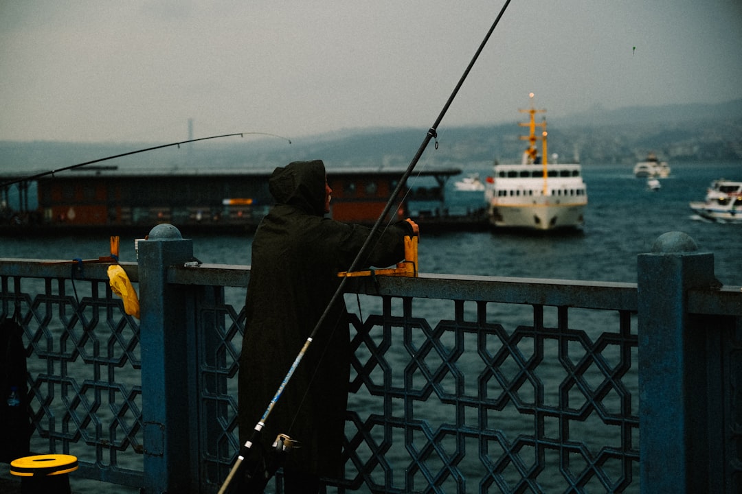 An action shot of a fisherman straining to reel in a large fish, with the rod bent and water splashing, capturing the excitement of the catch.