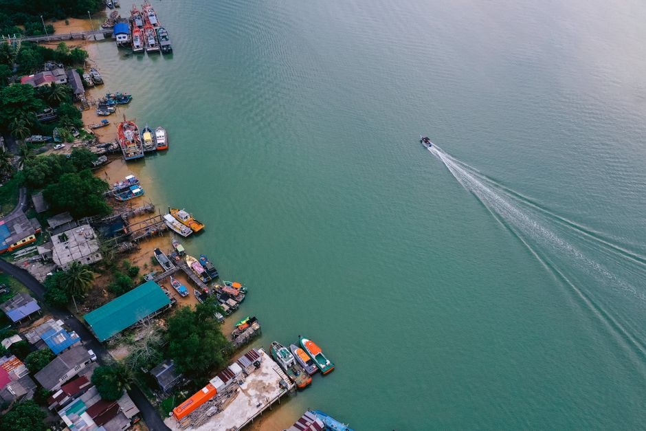 An aerial view of a sleek fishing boat tied to the dock of an impressive waterfront property in a coastal marsh area.