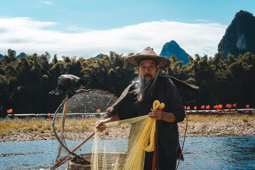 Modern fisherman in outdoor gear sits on a boat, looking at a tablet screen, symbolizing the use of data and technology to...